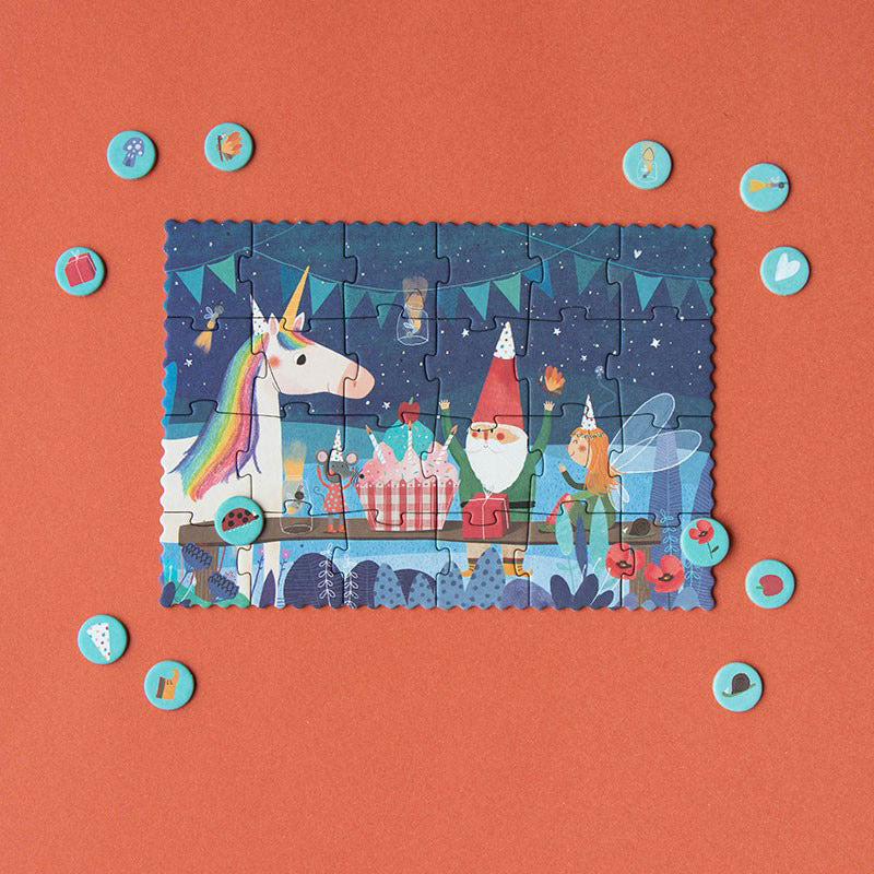 Das Puzzle zeigt ein Einhorn, einen Zwerg, eine Maus und eine Fee am Tisch vor einem Geburtstagsmuffin.