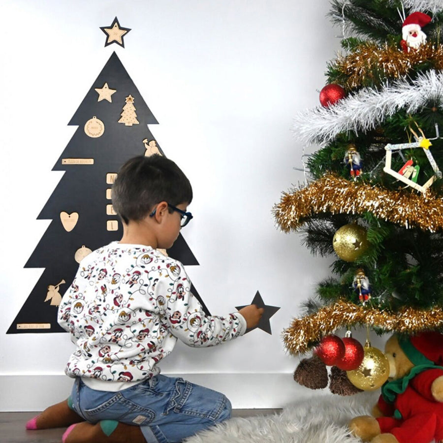 Ein Junge spielt mit den Magneten an der Magnettafel Tannenbaum von Ferflex neben dem richtigen Tannenbaum.