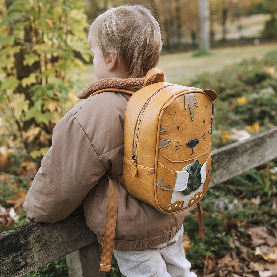 Kind trägt den Rucksack Tiger auf einem Ausflug ins Grüne.