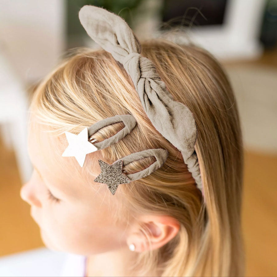 Mädchen trägt den Haarreifen und zwei Sternenspängchen im Haar. Sie trägt die Farbe taupe.