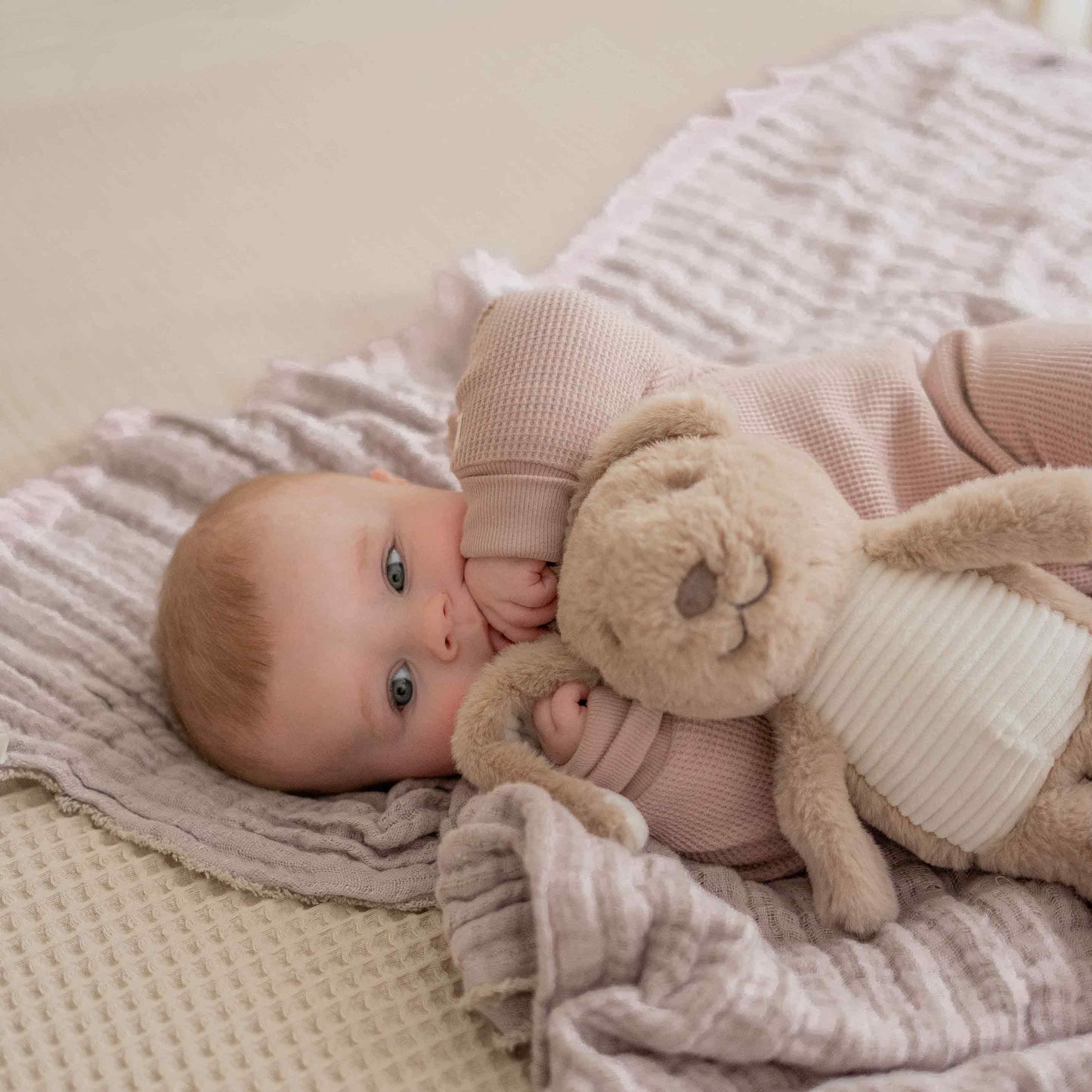 Baby spielt mit dem Heartbeat Comforter Hase Milo auf der Spieldecke