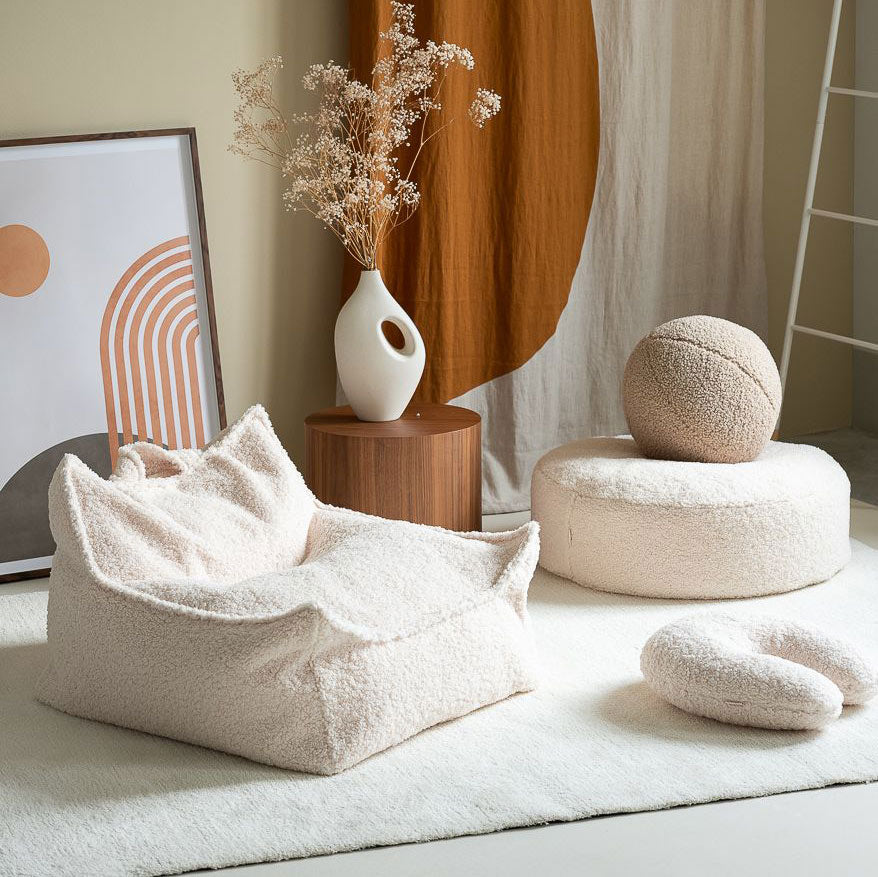 Kindersessel von Wigiwama in der Farbe creme. Daneben stehen weitere Accessoires von Wigiwama.