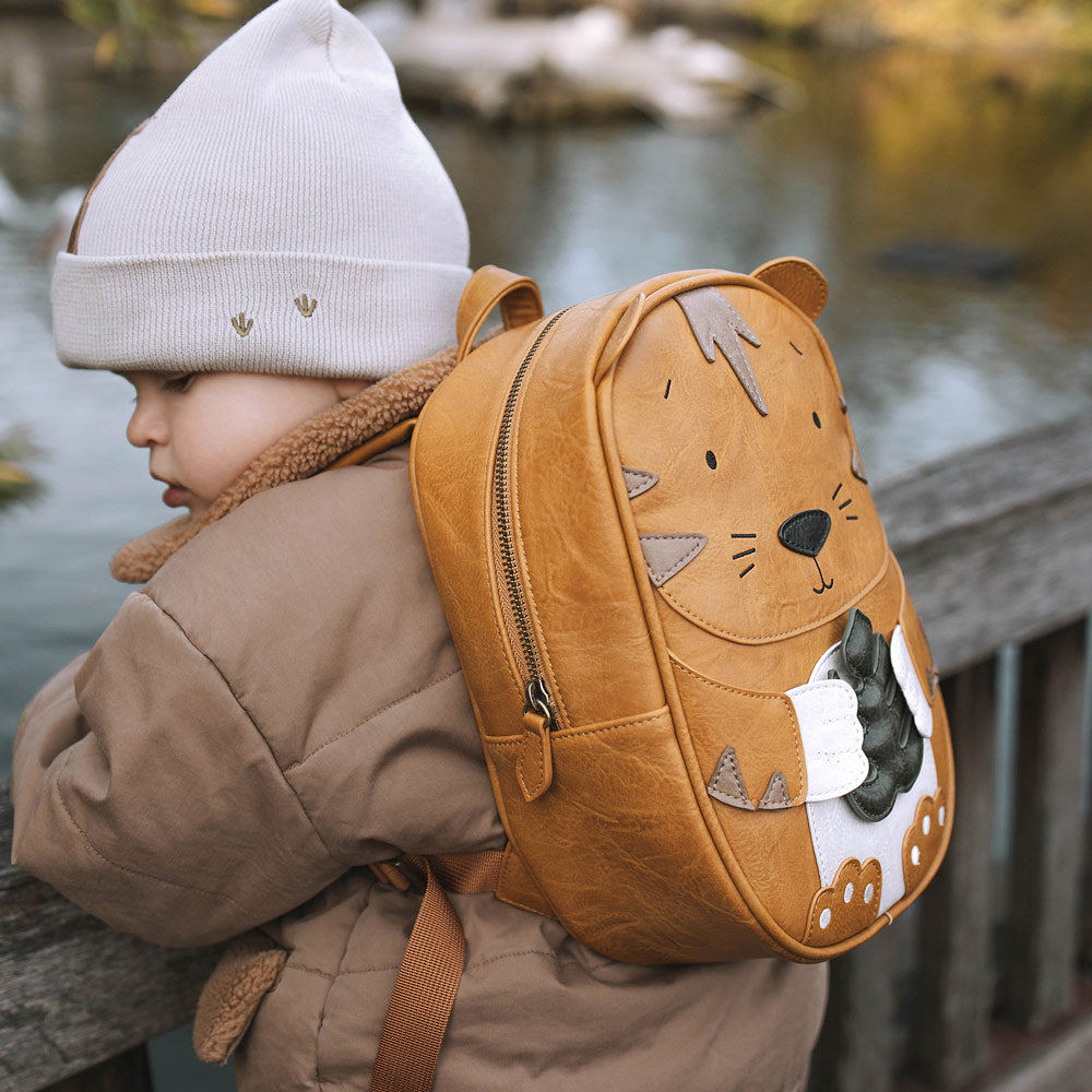 Kind trägt den Rucksack Tiger an einem See.
