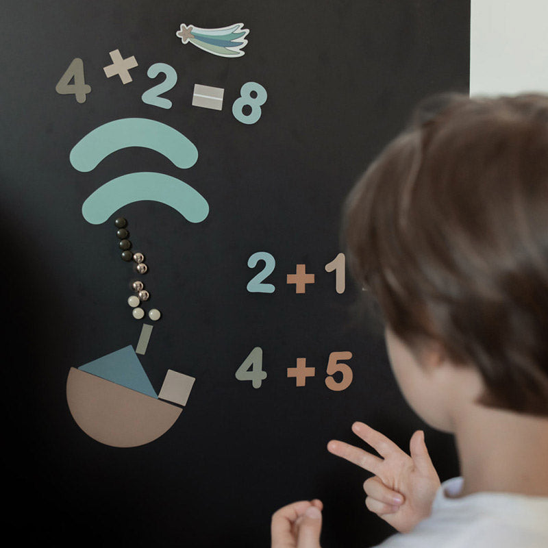 Kind rechnet vor der Magnettafel mit den Zahlen-Magneten von Ferflex