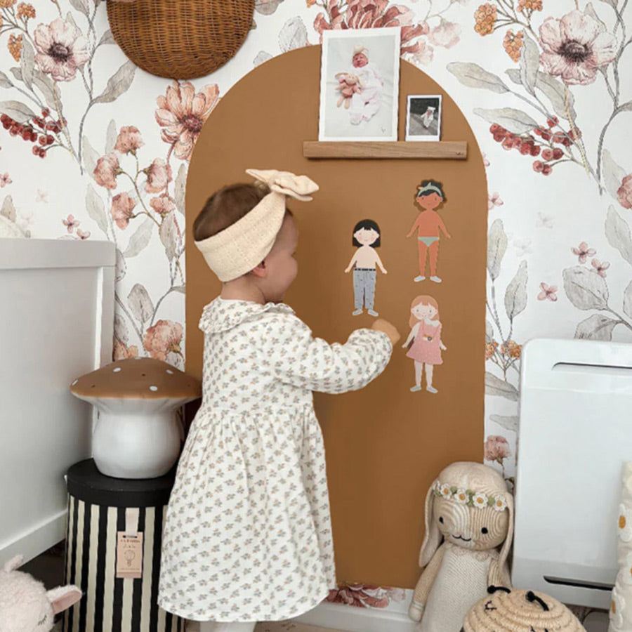 Mädchen spielt mit der Magnettafel in der Farbe Karamell, wo sie die Magnete Mädchen gerade anzieht