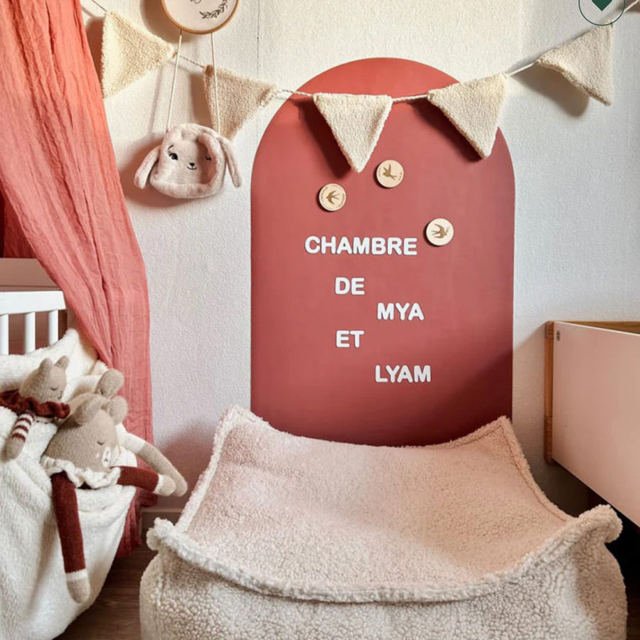 Magnettafel in der Farbe Terracotta, die in einem Kinderzimmer hängt. Davor steht ein Sitzsack von Wigiwama