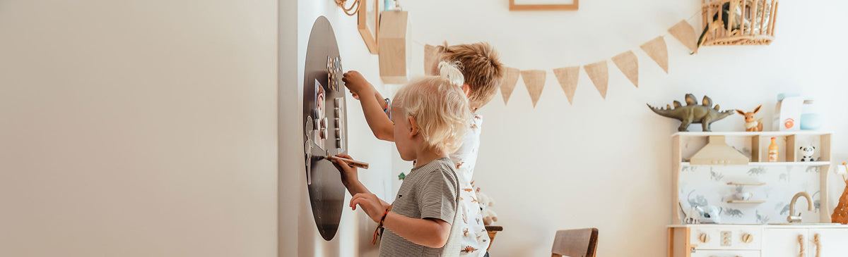 Zwei Kinder spielen und malen an der Magnettafel im Kinderzimmer