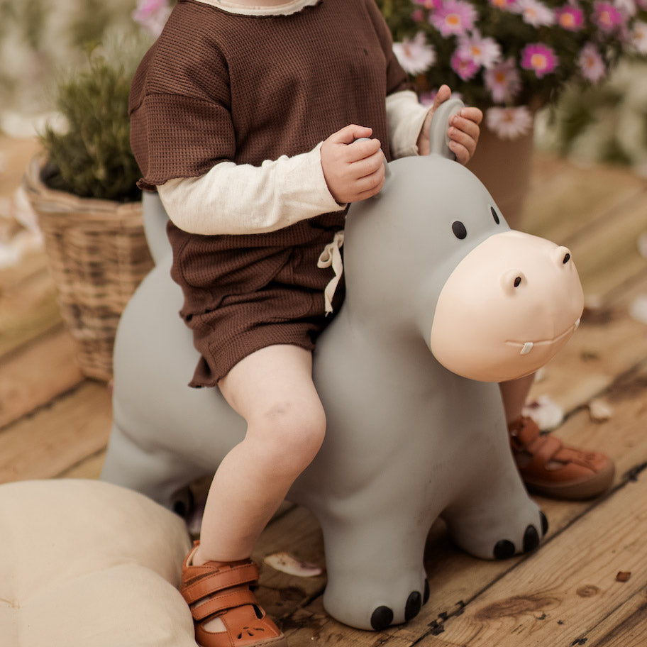 Kind sitzt auf dem Nilpferd Hippo Springtier auf der Terrasse