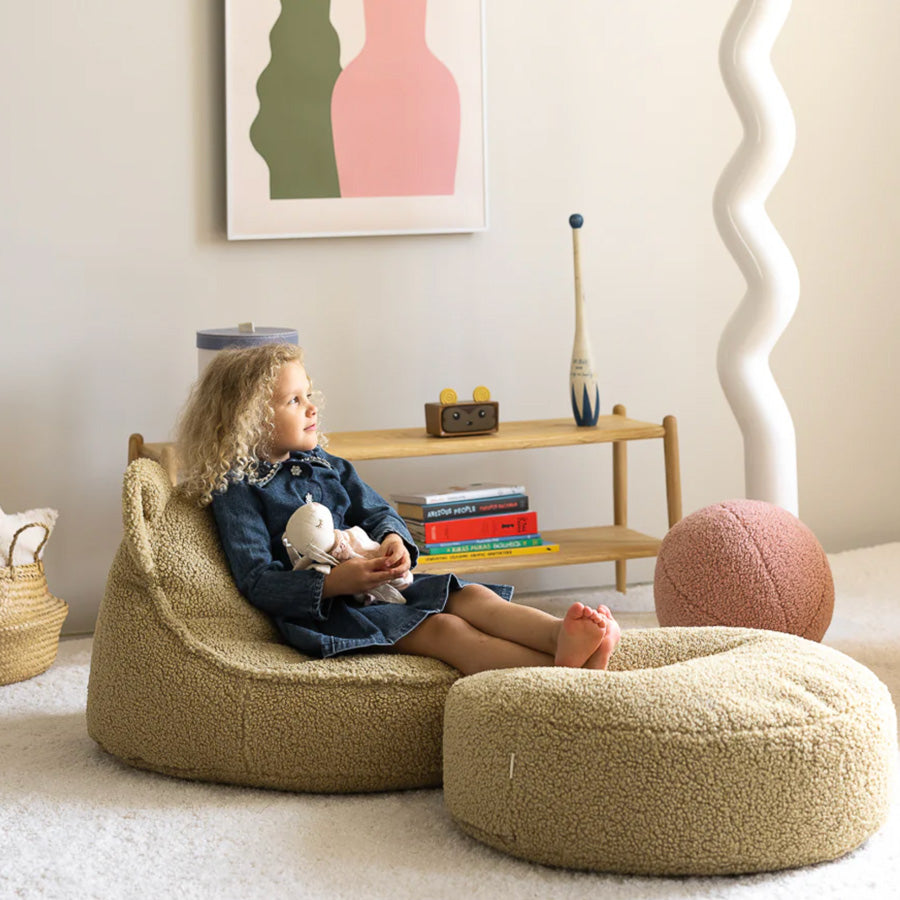 Runder Sitzsack Ottoman für Kinder von Wigiwama in der Farbe Matcha. Kind sitzt entspannt auf der Kombination Bärensitzsack und Ottoman.