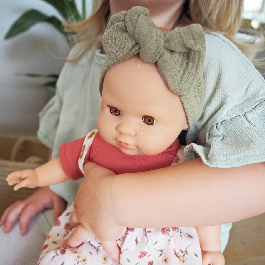 Mädchen hält die Spielzeugpuppe im Arm, eine Freundin, die man überall mitnehmen kann