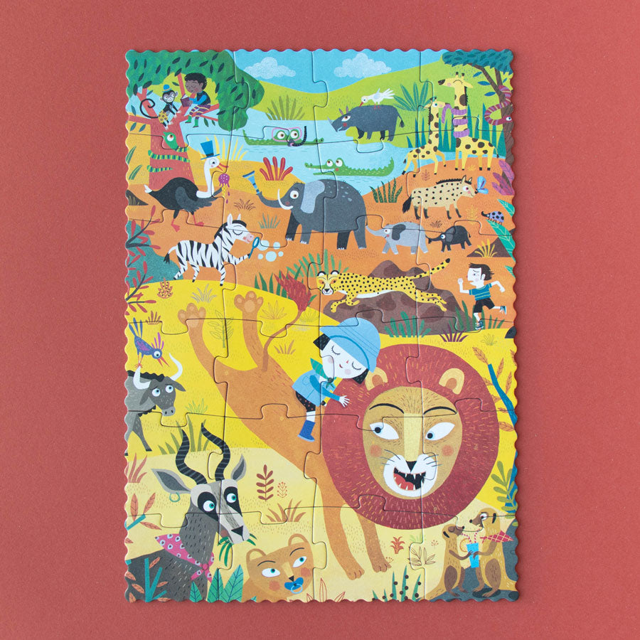 Das Puzzle zeigt ein Mädchen, dass auf einem Löwen reitet, sowie viele weitere Tiere der Savanne.