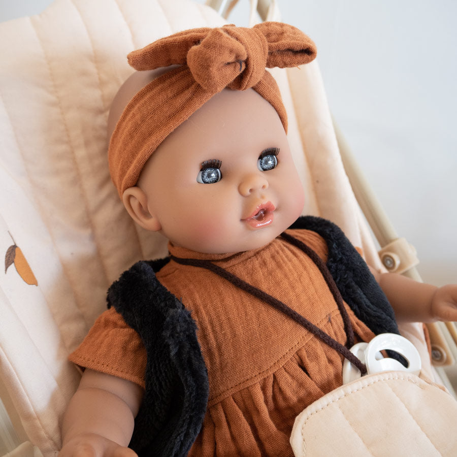 Puppe von Paola Reina mit einem braunen Kleid und Stirnband und einer schwarzen kuscheligen Weste