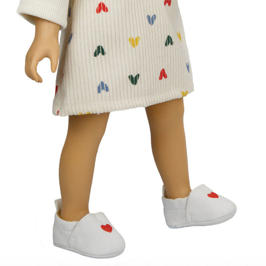 Puppe trägt weiße Slipper mit rotem Herzen drauf