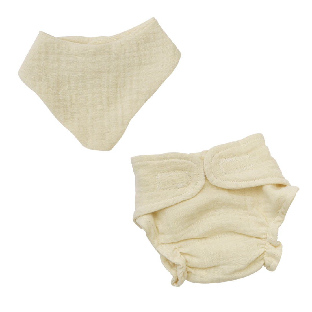 Das Set von Heless besteht aus einem Lätzchen und einer Windel aus einem cremefarbenen Musslinstoff.