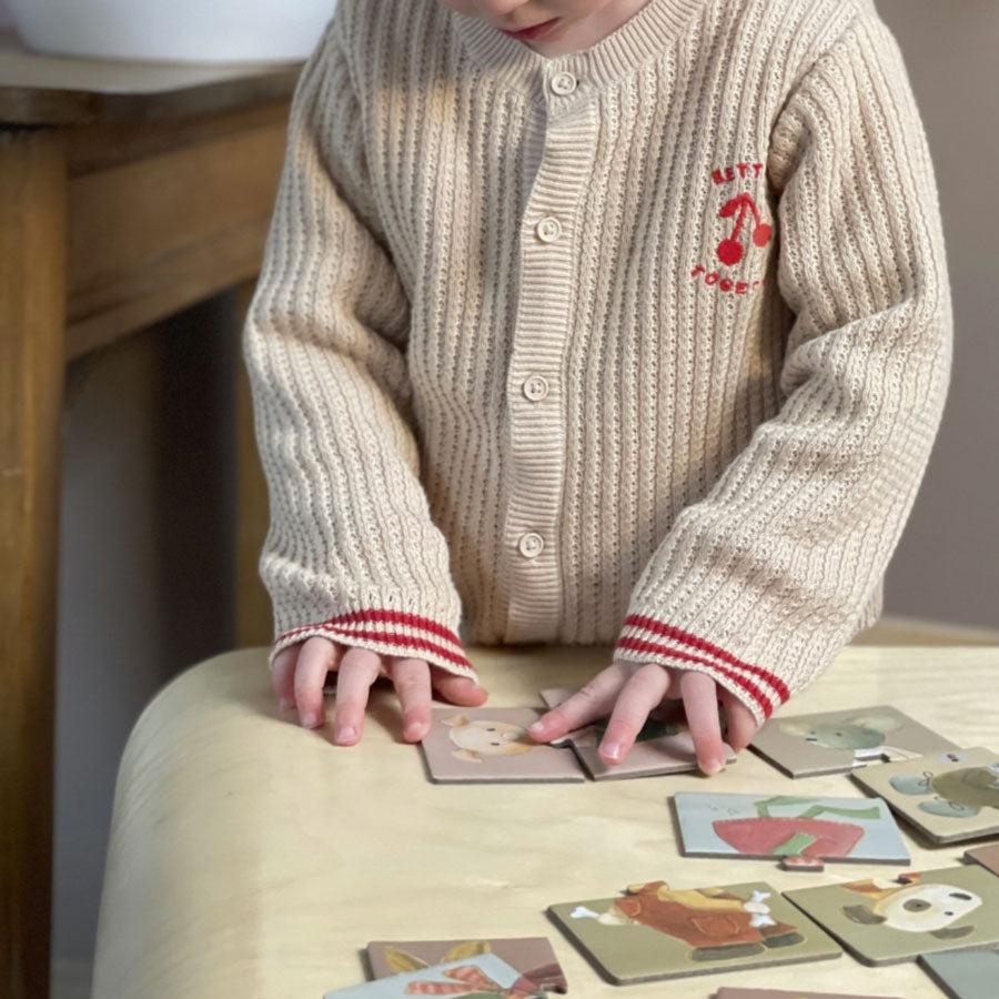 Kind puzzelt das Tier-Zurdnungsspiel, wo der Tierkopf zum Körper zugeordnet werden muss