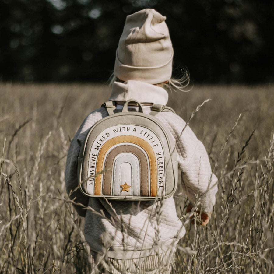 Kind trägt den Rucksack Regenbogen Boho in den Farben olivgrün, brau, hellblau und ocker