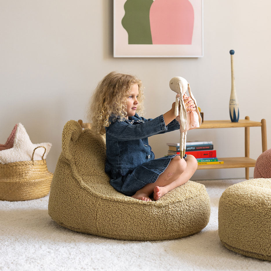 Mädchen spielt auf dem Kindersessel in der Farbe Matcha von Wigiwama.