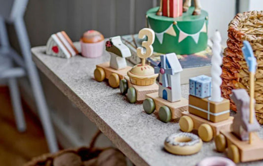 Geburtstagszug auf dekoriertem Tisch mit Hase, Geschenken, Windmühle, Kuchen und Pilz