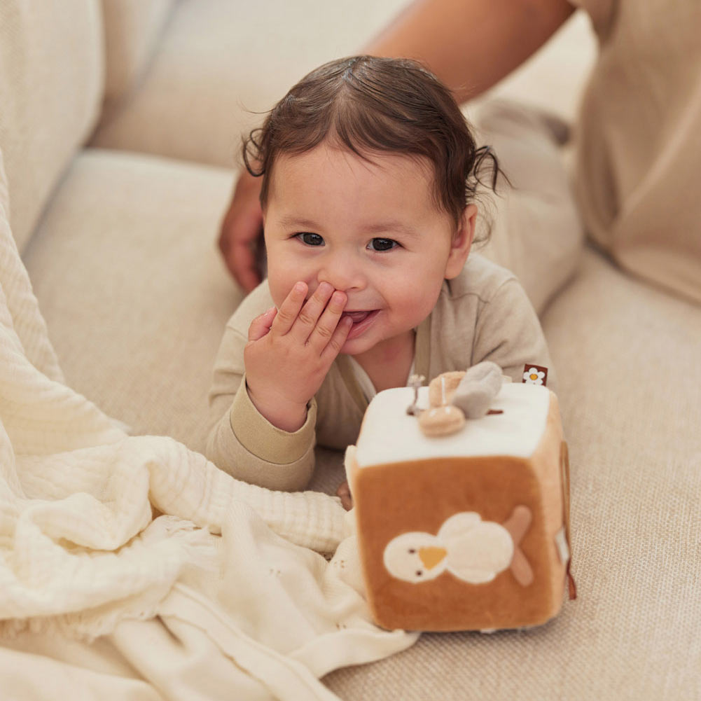 Baby spielt mit dem Aktivitätswürfel und freut sich über die verschiedenen Seiten des Würfels