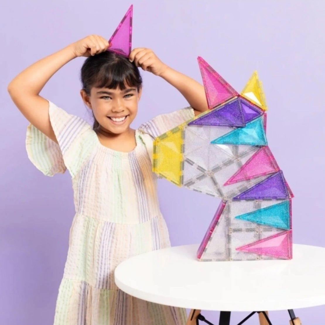 Mädchen zeigt ihr gebautes Einhorn mit den Glitzer-Magetbausteinen von Connetix