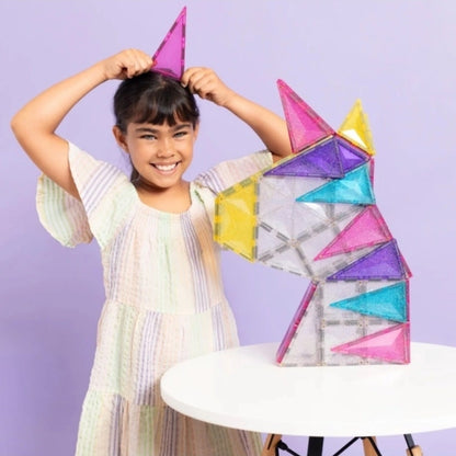 Mädchen zeigt ihr gebautes Einhorn mit den Glitzer-Magetbausteinen von Connetix