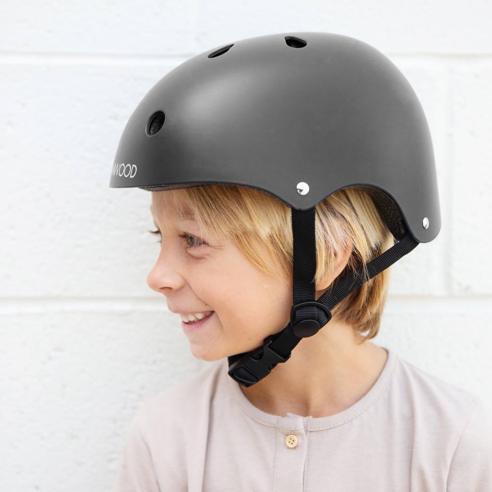 Banwood-Helm in der Farbe schwarz, getragen von einem blonden Jungen, der zur Seite lächelt