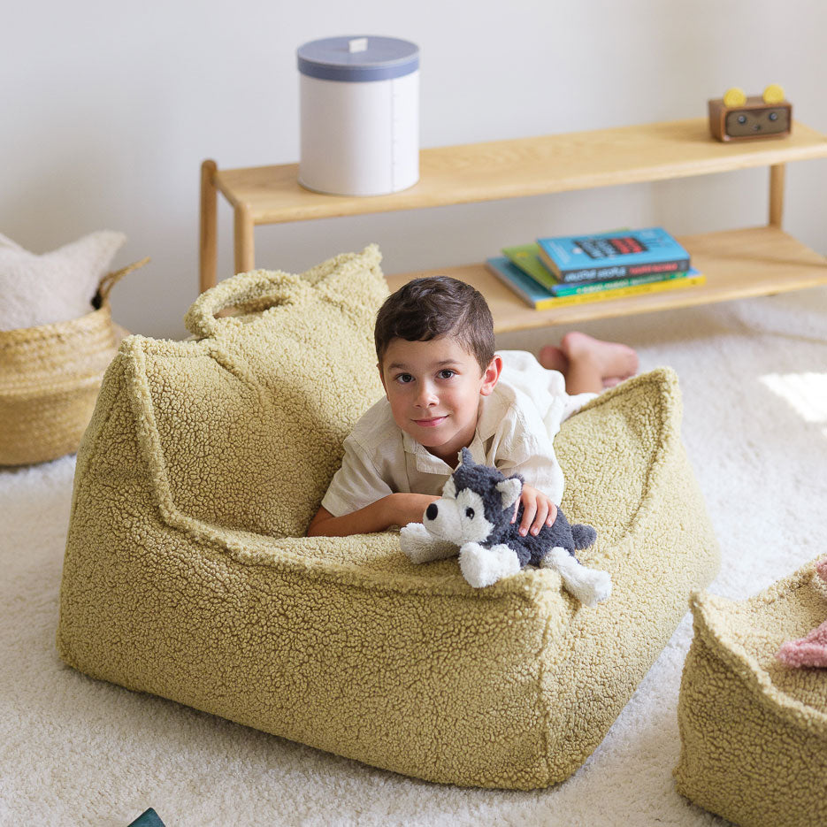 Junge liegt auf dem Kindersessel von Wigiwama in der Farbe Matcha