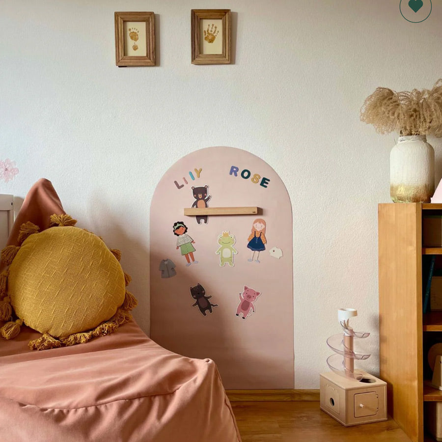 Magnettafel in der Farbe rosa/beige hängt im Kinderzimmer mit verschiedenen Magneten zum Spielen