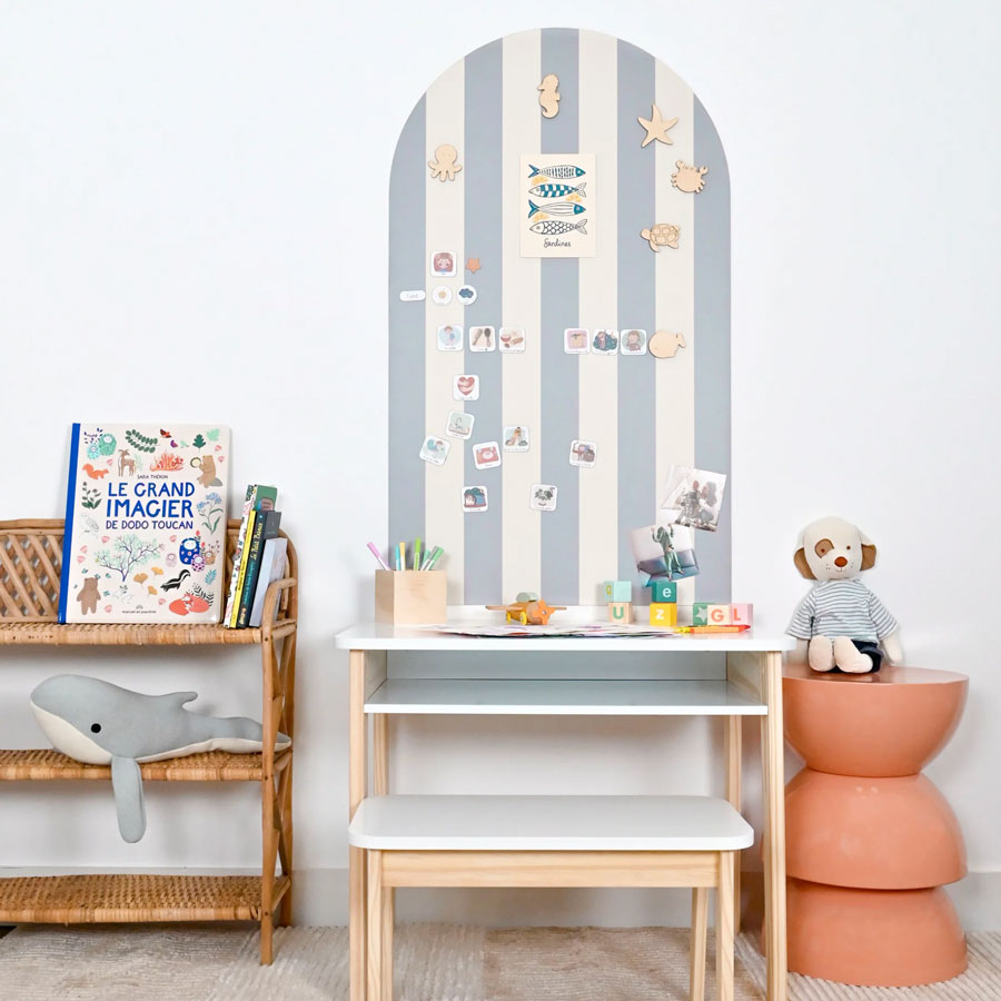 Gestreifte Magnettafel in der Farbe hellblau und creme mit verschiedenen Magneten im Kinderzimmer