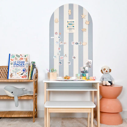 Gestreifte Magnettafel in der Farbe hellblau und creme mit verschiedenen Magneten im Kinderzimmer