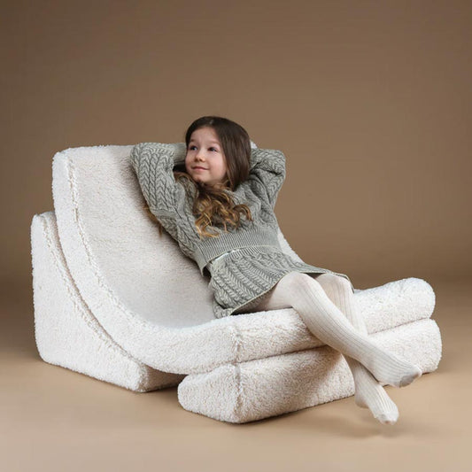 Mädchen sitzt entspannt auf dem Moon Chair Sessel in der Farbe Creme.