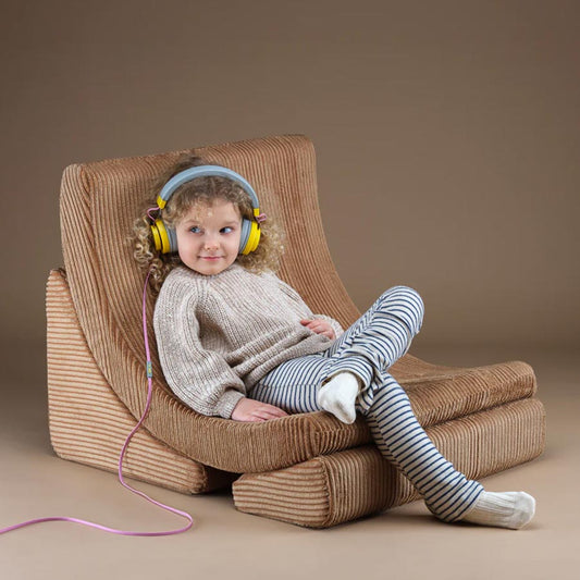 Mädchen sitzt entspannt mit Kopfhörern auf dem Moon Chair in der Farbe Toffee. 