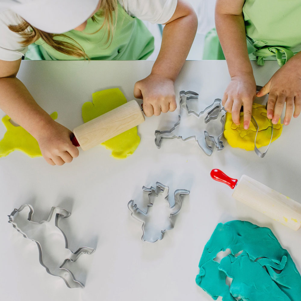 Zwei Kinder spielen mit bunter Knete. Sie rollen die Knete aus und nutzen die Ausstechformen von Pippi Langstrumpf.