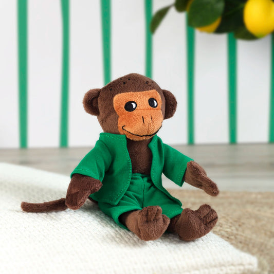 Der braune Affe Herr Nilsson hat ein hellbraunes Gesicht mit aufgesticktem Gesicht. Der Affe trägt eine grüne Hose und ein passend grünes Jäckchen. 