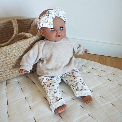 Die Puppe Malou kommt mit exklusiver Puppenkleidung von PAOLA REINA, nämlich einem Sweater, einer Musselin-Hose und einem Stirnband sowie einer Schleife für den Kopf.