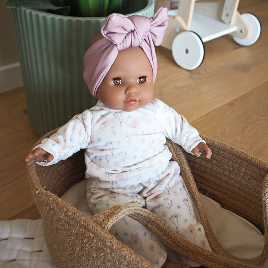 Puppe mit dunklerer Haut, braunen Augen und einem schlichten Outfit in hellen Farben