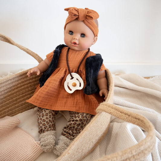 Puppe mit weichem Körper trägt ein hellbraunes Kleid mit schwarzer Weste und einer Leoleggings. Passend dazu hat die Puppe ein Stirnband in hellbraun. 