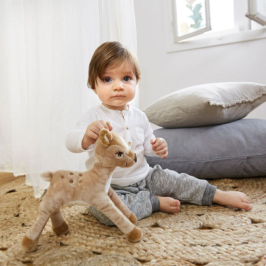Rehkitz Kuscheltier steht vor dem Kleinkind 