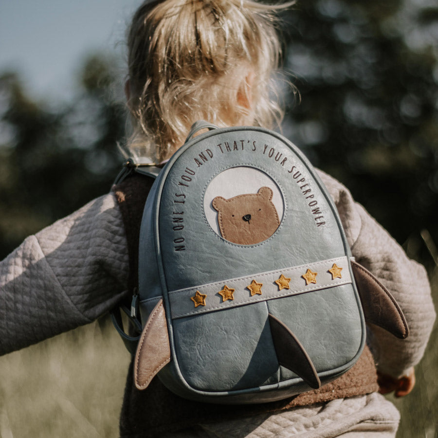 Mädchen läuft mit dem Rucksack Rakete auf dem steht: No one is you and that's your Superpower