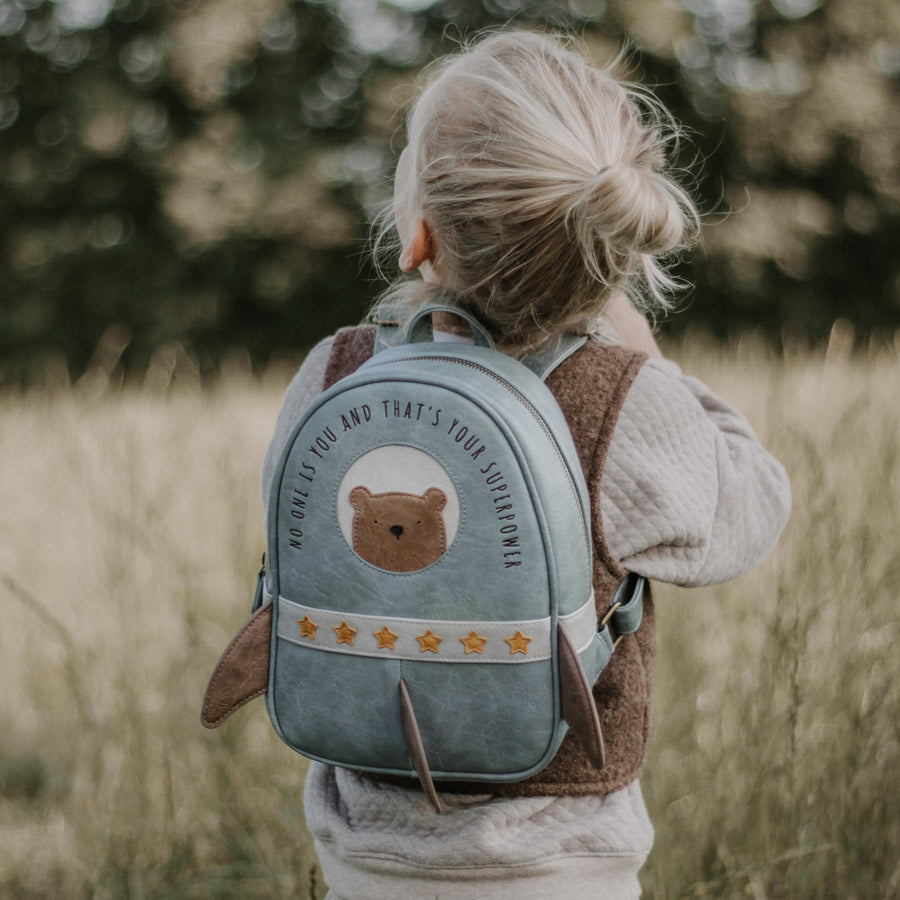 Mädchen trägt den Raketen-Rucksack it dem Bären in der Farbe blau mit süßen Details