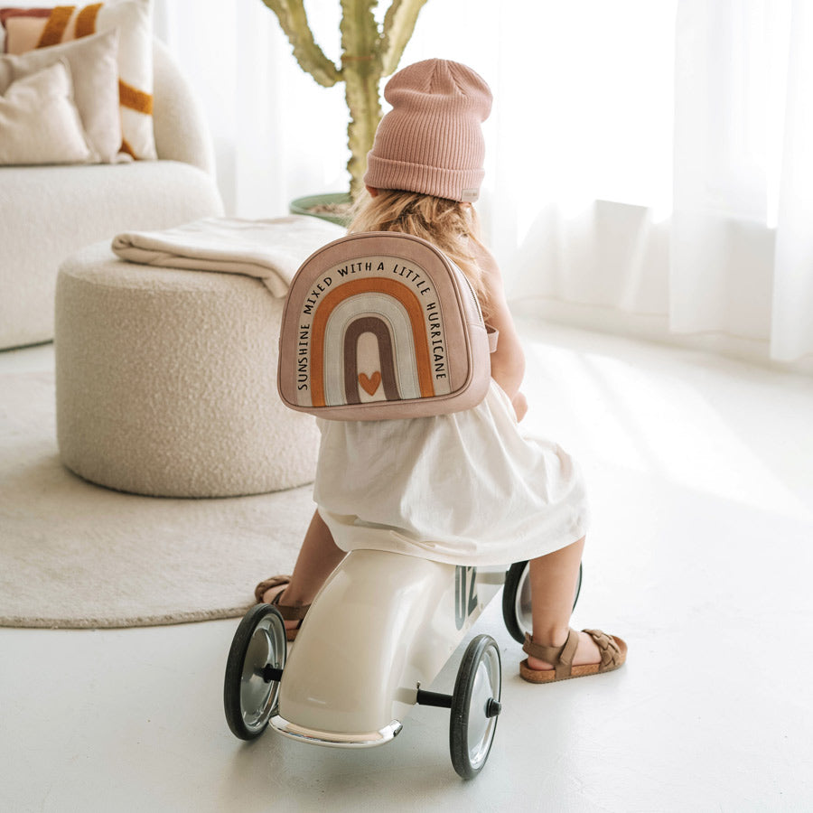 Kind trägt den Kita-Rucksack Regenbogen mit dem Spruch: Sunshine Mixed with a Little Hurricane