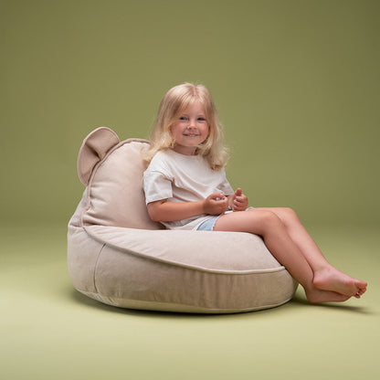 Mädchen sitzt auf dem Sitzsack Bär für Kinder von Wigiwama in der Farbe beige. 