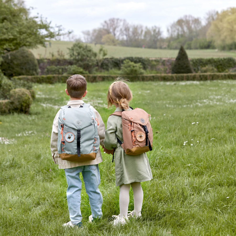 Junge und Mädchen stehen auf einer Wiese mit den Wanderrucksäcken von Lässig. 