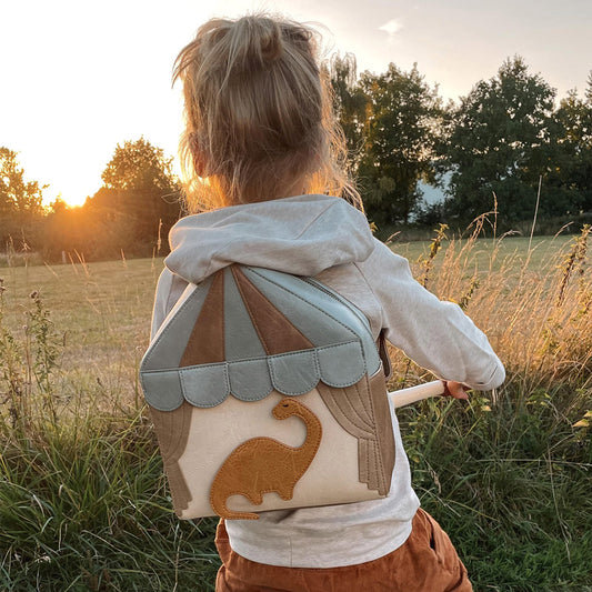 Kind trägt den Rucksack Noah auf dem Rücken und fährt dabei Laufrad